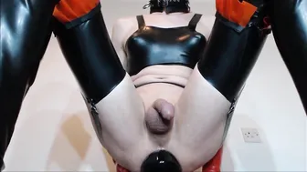 Travesti en latex joue avec un plug anal en talons