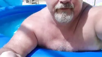 Papá oso desnudo relajándose junto a la piscina
