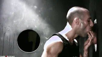 Muscular hunk sucks huge cock through glory hole